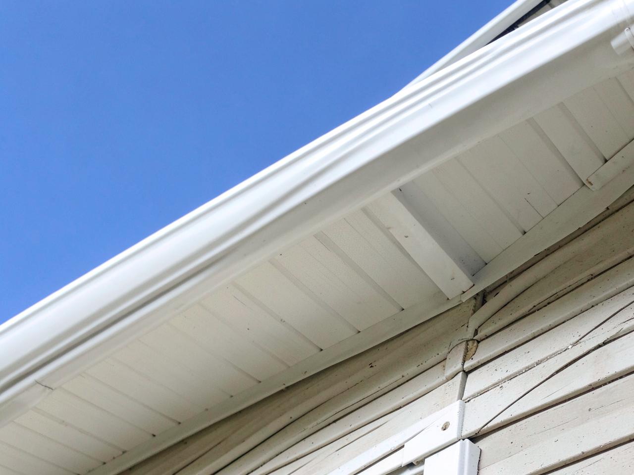 White soffit, fascia and a seamless gutter along a home roofline against blue sky